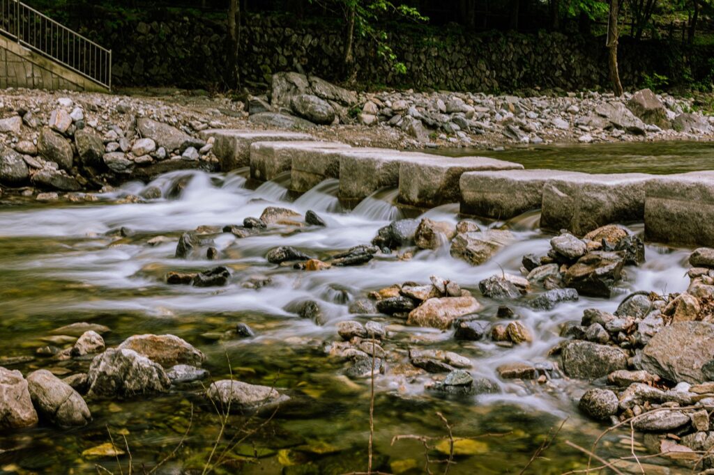 A peaceful stone bridge over a flowing river in Gyeonggi-do, highlighting natural beauty and tranquility.