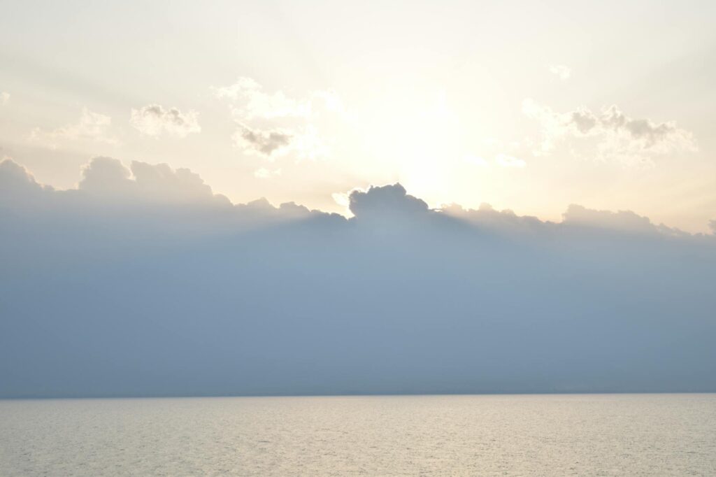 Gentle sunrise over a calm sea with soft clouds creating a peaceful seascape.