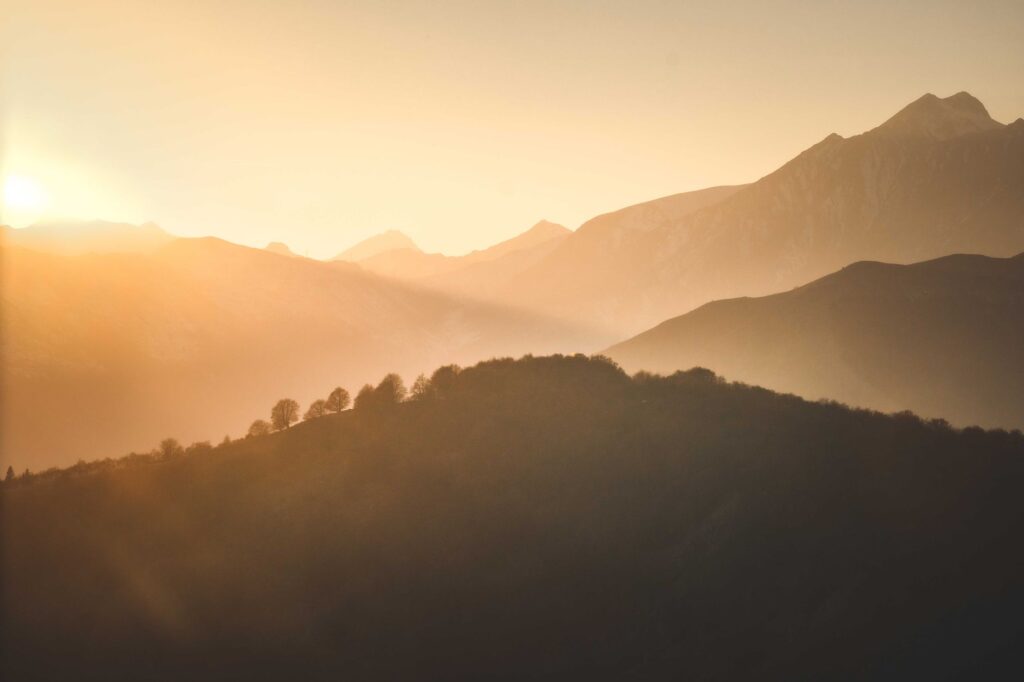 A tranquil sunrise casting warm hues over a misty mountain landscape.