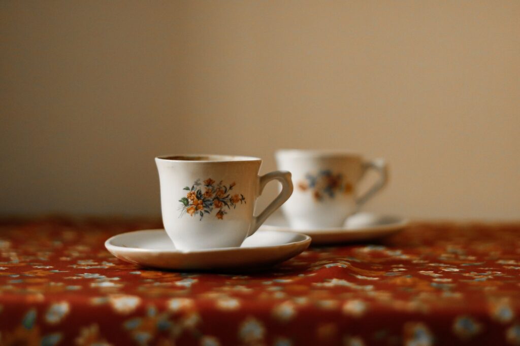 Two elegant floral teacups on a richly patterned tablecloth, creating a cozy, inviting atmosphere.